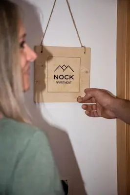 a woman pointing at a nook sign hanging on a wall at Nock Apartment Dolomites in South Tyrol - Italy in Nova Ponente