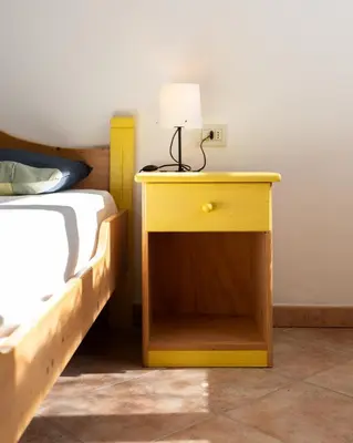 a yellow table with a lamp on it next to a bed at El Casel dei Masi in Grumes