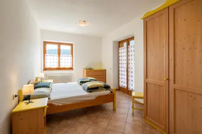 a bedroom with a bed and a wooden cabinet at El Casel dei Masi in Grumes