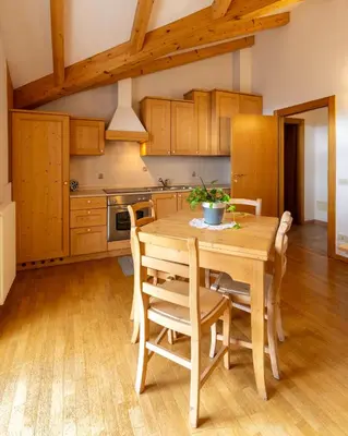 a kitchen with a wooden table and chairs at El Casel dei Masi in Grumes