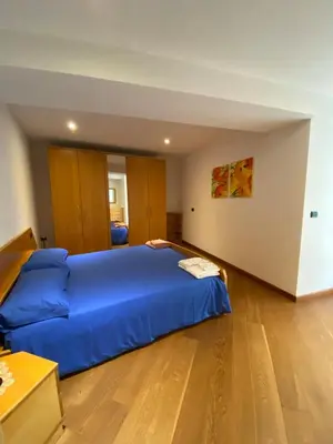 a bedroom with a blue bed and a wooden floor at El Polse - Appartmento per 5 persone in Ziano di Fiemme