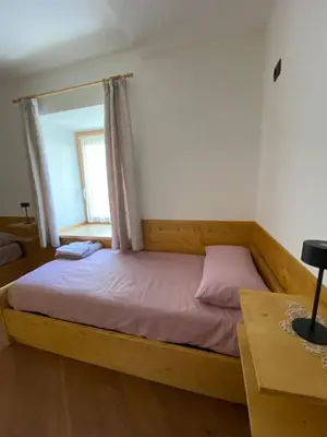a bedroom with a wooden bed with a window at El Polse - Appartmento per 5 persone in Ziano di Fiemme