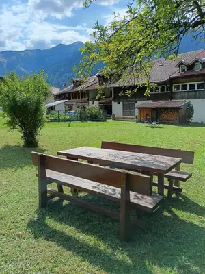 a wooden bench sitting in the grass in front of a house at El Polse - Appartmento per 5 persone in Ziano di Fiemme