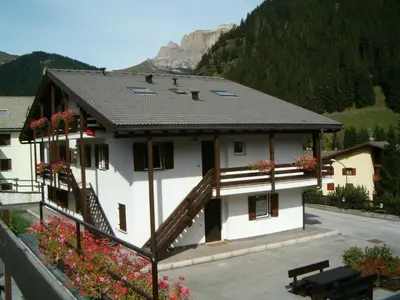 a large white building with a balcony with flowers at Residence Canazei in Alba di Canazei