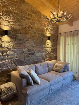 a couch in a room with a stone wall at Alloggio per Milano-Cortina 2026 a ValdiFiemme in Carano