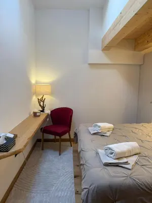 a room with two beds and a desk and a red chair at Alloggio per Milano-Cortina 2026 a ValdiFiemme in Carano