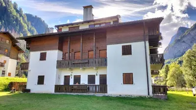 a large building with a balcony on a grass field at El Zirum Boscoverde in Sottoguda