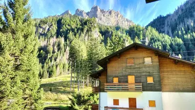 a wooden house in front of a mountain at El Zirum Boscoverde in Sottoguda