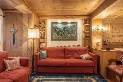 a living room with a red couch and a painting at Casa Bucaneve 2, confortevole a due passi dal centro in Cortina dʼAmpezzo