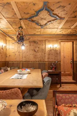 a room with a wooden ceiling with a table and chairs at Casa Bucaneve 2, confortevole a due passi dal centro in Cortina dʼAmpezzo