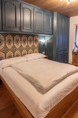 a large bed in a room with blue cabinets at Casa Bucaneve 2, confortevole a due passi dal centro in Cortina dʼAmpezzo