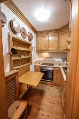 a kitchen with wooden cabinets and a wooden floor at Casa Bucaneve 2, confortevole a due passi dal centro in Cortina dʼAmpezzo