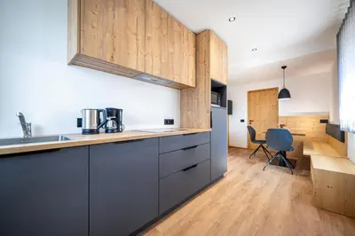 a kitchen with gray cabinets and a dining room at Apartments Raffl in Ortisei
