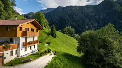 a house on the side of a green hill at Apartments Raffl in Ortisei