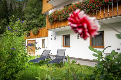 a group of chairs in front of a building with flowers at Apartments Raffl in Ortisei