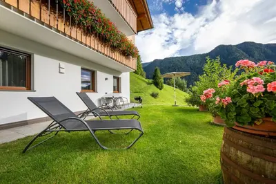 a group of chairs sitting on a lawn with flowers at Apartments Raffl in Ortisei