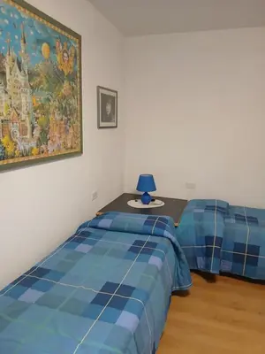 a bedroom with two beds and a table with a lamp at Casa Soppelsa 1 in Moena