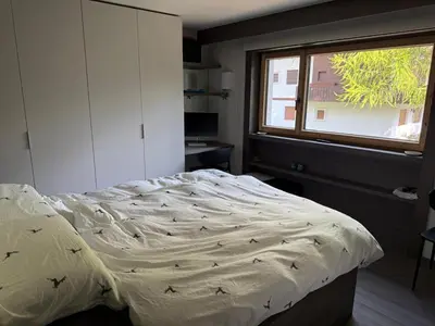 an unmade bed in a bedroom with a window at Dimora Alverà 19 in Cortina dʼAmpezzo