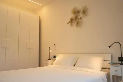 a bedroom with a white bed and a plant on the wall at Talvera Dream - City center, Rooftop, Garage & Jacuzzi in Bolzano