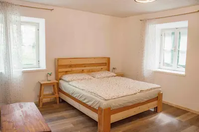 a bedroom with a wooden bed and two windows at Dhea's Little House in Bolzano
