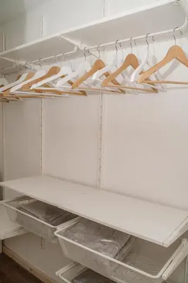 a closet with white shelves and wooden hangers at Dhea's Little House in Bolzano
