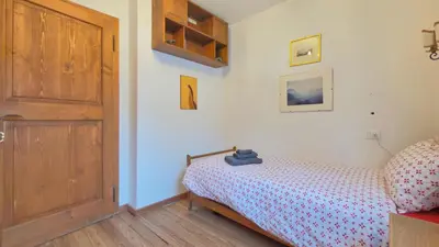 a bedroom with a bed and a wooden door at Homeby, Ca' Del Molin in Cortina dʼAmpezzo