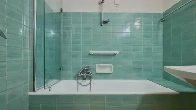 a green tiled bathroom with a shower and a sink at Homeby, Ca' Del Molin in Cortina dʼAmpezzo
