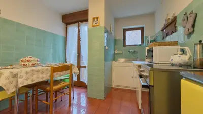 a kitchen with a table and a kitchen with green tiles at Homeby, Ca' Del Molin in Cortina dʼAmpezzo