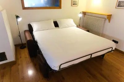 a bedroom with a bed with white sheets and a lamp at Dolomites Garden Flat near Cortina in Villanova