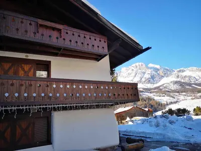 a building with a balcony with snow covered mountains at Apartment with Dolomites view in Cortina dʼAmpezzo
