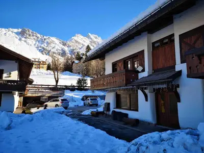a snow covered building with cars parked in front of it at Apartment with Dolomites view in Cortina dʼAmpezzo