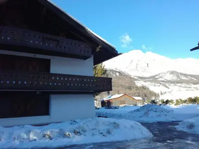 a snow covered building with a mountain in the background at Apartment with Dolomites view in Cortina dʼAmpezzo