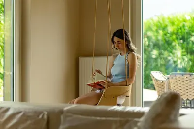 a woman sitting on a swing reading a book at Villa Ilaria in Lagundo