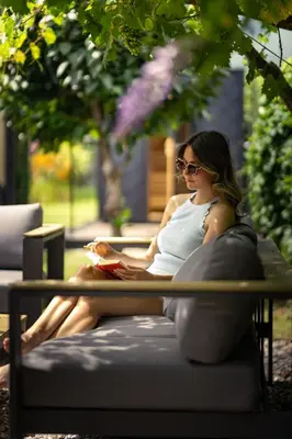a woman sitting on a bench reading a book at Villa Ilaria in Lagundo