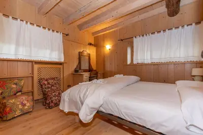 a bedroom with a bed and a chair in a room at Serrai Lodge in Sottoguda