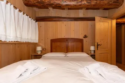 a large bed in a room with wooden walls at Serrai Lodge in Sottoguda