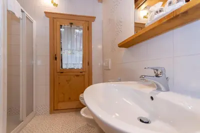 a white bathroom with a sink and a toilet at Serrai Lodge in Sottoguda