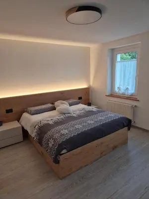 a bedroom with a large wooden bed with a window at Casa Celeste Dolomiti in Frassenè