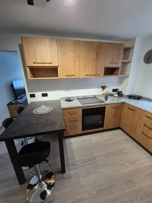 a kitchen with wooden cabinets and a table with a chair at Casa Celeste Dolomiti in Frassenè