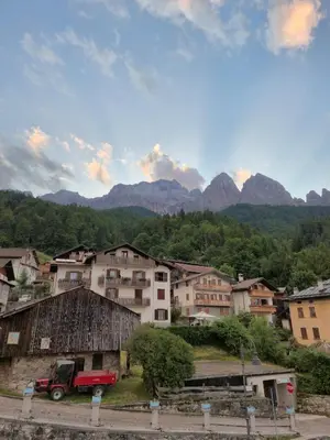 a group of buildings in a town with mountains in the background at Casa Celeste Dolomiti in Frassenè