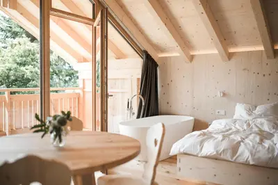a bedroom with a tub and a table and a bed at Zalnerhof Urlaub am Bauernhof in Luson