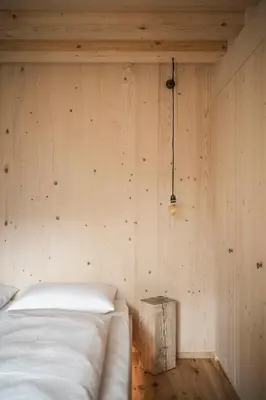 a bedroom with a white bed and a wooden wall at Zalnerhof Urlaub am Bauernhof in Luson