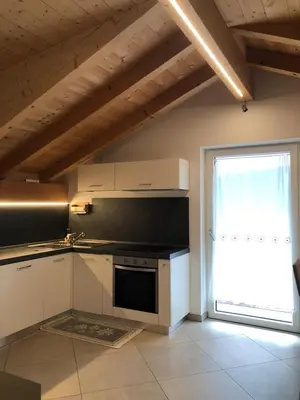 a kitchen with white appliances and a large window at villa morena in Cavalese