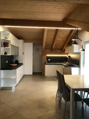 a kitchen with white cabinets and a table with chairs at villa morena in Cavalese