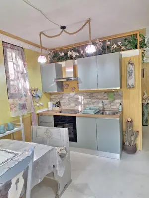a kitchen with white cabinets and a sink and a table at Alessandra's House Mountain in Masarè