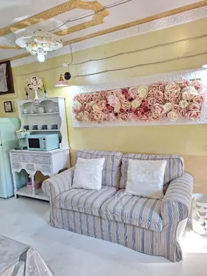 a living room with a couch and flowers on the wall at Alessandra's House Mountain in Masarè