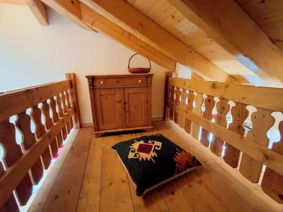 an attic room with a wooden staircase and a rug at Maso Tre Cucù by Go New Location in Cavalese