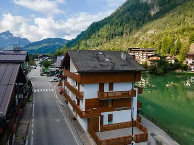 a building with wooden balconies next to a river at Suite Civetta in Masarè