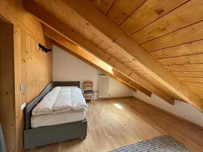 a bedroom with a bed in a room with wooden ceilings at Elegante Appartamento in Campitello fi Fassa in Campitello di Fassa
