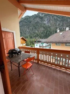 a balcony with a table and a grill on it at Elegante Appartamento in Campitello fi Fassa in Campitello di Fassa